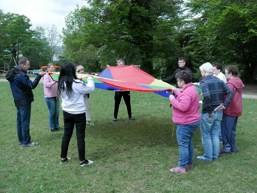 Bild zeigt eine Gruppe Menschen beim gemeinsamen Spiel auf einer Wiese.